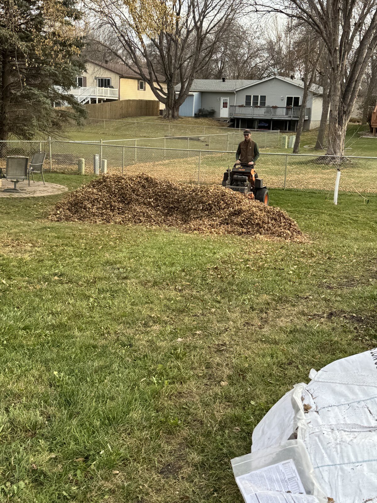 Perfect Turf mowing through a large leaf pile during a fall yard cleanup