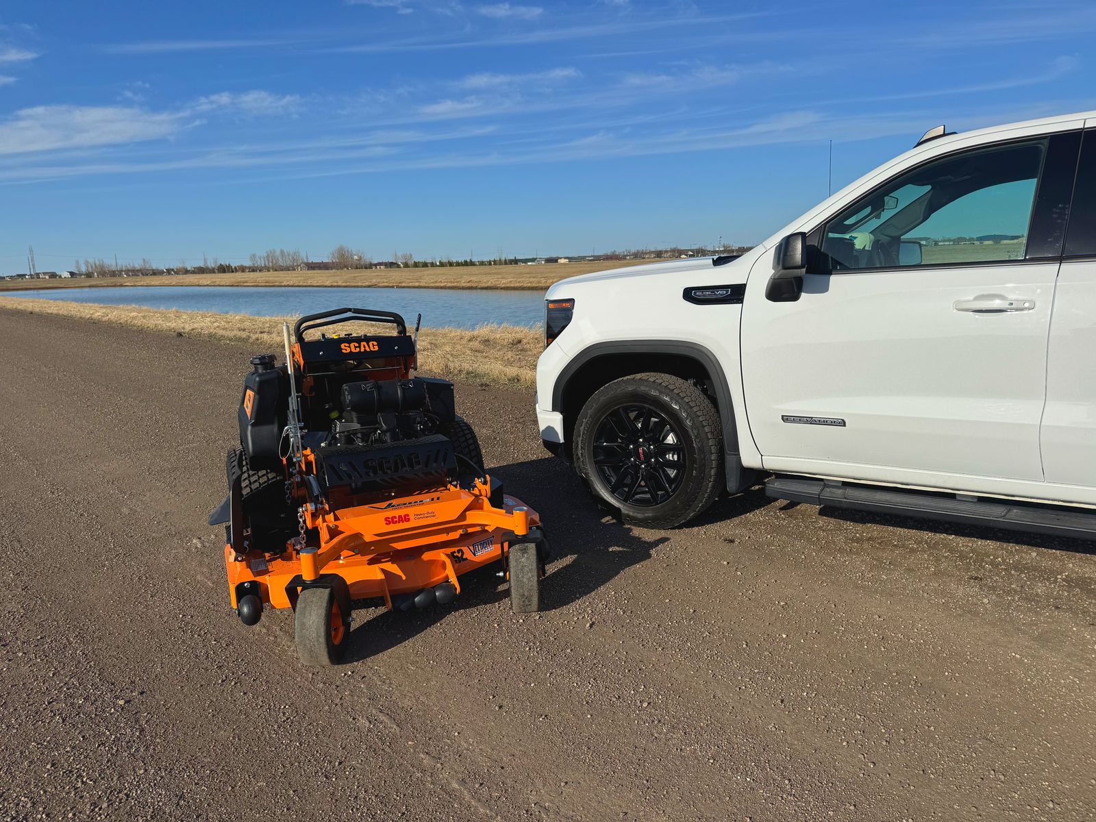 Scag zero-turn mower and Perfect Turf work truck on a prairie road